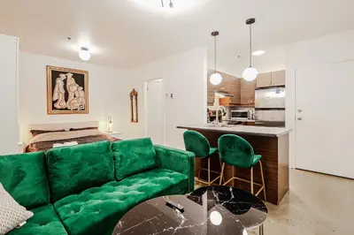 a living room with a green couch and a kitchen at Escapade Chic au Vieux-Port in Montréal