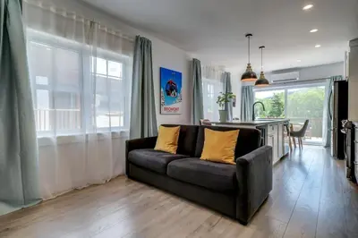 a living room with a black couch and a kitchen at 851 condo in Bromont Vieux Village mountain view in Bromont