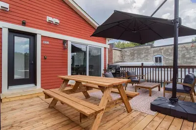 a wooden picnic table with an umbrella on a deck at 851 condo in Bromont Vieux Village mountain view in Bromont