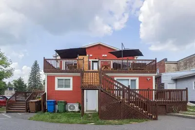 a red house with a deck with an umbrella at 851 condo in Bromont Vieux Village mountain view in Bromont