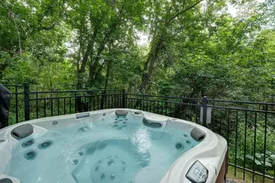 a jacuzzi tub on a balcony with trees at 853 condo in Bromont Vieux Village mountain view in Bromont