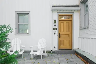 two white chairs sitting outside of a house with a door at Loft at 913 Shefford in Bromont