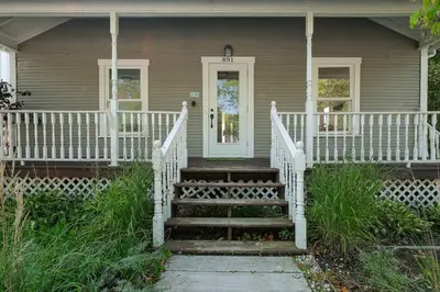 a house with a white porch and stairs to a door at 891 shefford 4-bedroom house in Bromont
