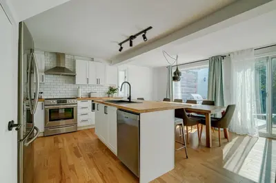 a kitchen with white cabinets and a table with a dining room at 891 shefford 4-bedroom house in Bromont