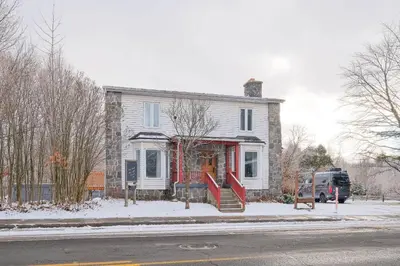 a white house with a red front door in the snow at 951 Shefford 4 bedrooms house in Bromont