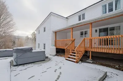 a house with a deck and snow on the ground at 951 Shefford 4 bedrooms house in Bromont