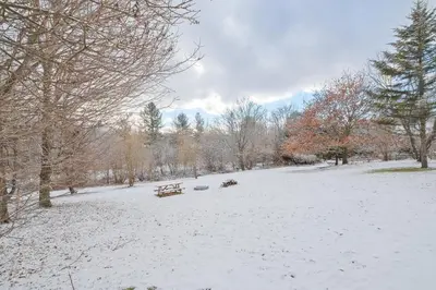 a snow covered park with a bench and trees at 951A Shefford Bromont 3 bedrooms in Bromont