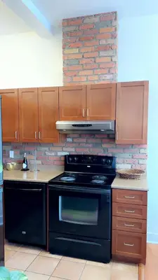 a kitchen with a black stove and a brick wall at Spacious Condo with a Bright Interior in Montréal