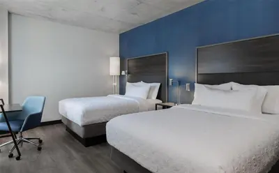 a hotel room with two beds and a chair at Tru By Hilton Montréal centre-ville in Montréal
