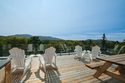 a deck with white chairs and a wooden table and a picnic table at room with private bathroom 837 shefford suite 105 in Bromont