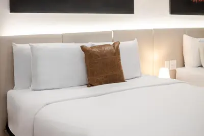 a large white bed with a brown pillow on it at Olympia Hotel by Lodgo in Montréal