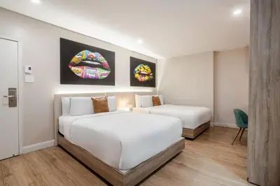 a white bedroom with two beds and a chair at Olympia Hotel by Lodgo in Montréal
