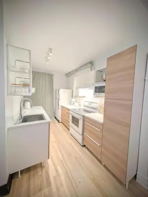 a kitchen with white appliances and a wooden floor at Appartement cosy au mois proche du Stade Olympique in Montréal