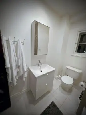 a white bathroom with a toilet and a sink at Appartement cosy au mois proche du Stade Olympique in Montréal
