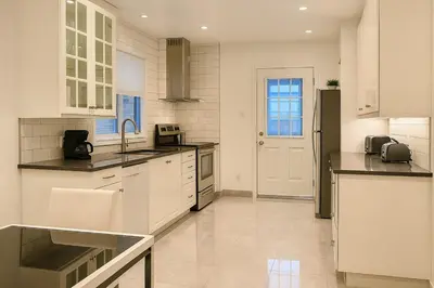 a large kitchen with white cabinets and appliances at Charming Vintage Home Park View Family-Ready in Montréal