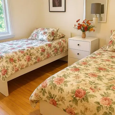 a bedroom with two beds and a vase of flowers at Charming Vintage Home Park View Family-Ready in Montréal