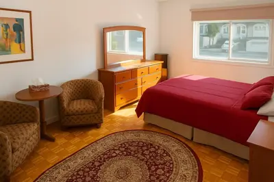 a bedroom with a red bed and a chair and a table at Chic 3BR Stay in Laval, Bright and Peaceful in Laval