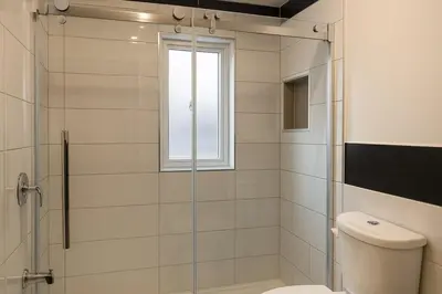 a bathroom with a shower with a toilet and a window at Sunny & Peaceful 1BR, Walk to UdM, HEC & Hospital in Montréal