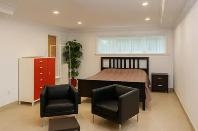 a bedroom with a bed and two black chairs at Stylish Furnished Modern Studio, Bright and Spacious 20 Minutes from Downtown in Montréal