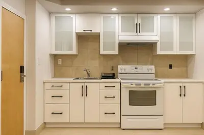 a kitchen with white cabinets and a sink at Stylish Furnished Modern Studio, Bright and Spacious 20 Minutes from Downtown in Montréal