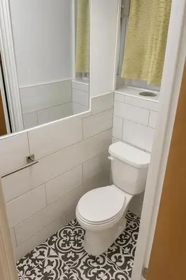 a bathroom with a white toilet and a mirror at Stylish Furnished Modern Studio, Bright and Spacious 20 Minutes from Downtown in Montréal