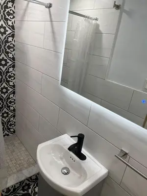 a white bathroom with a sink and a mirror at Stylish Furnished Modern Studio, Bright and Spacious 20 Minutes from Downtown in Montréal
