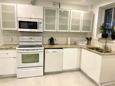 a kitchen with white cabinets and white appliances at Bright Renovated 4BR, Heart of Côte-des-Neiges, Montreal in Montréal