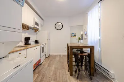 a kitchen with a table and a clock on the wall at Central 3BR downtown MTL Plateau Mont Royal in Montréal