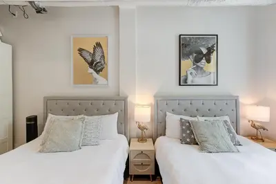 a bedroom with two beds with white sheets and two lamps at Le Galeria, MTLVR in Montréal