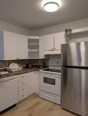 a kitchen with white cabinets and a stainless steel refrigerator at Stay close to Montreal in Longueuil