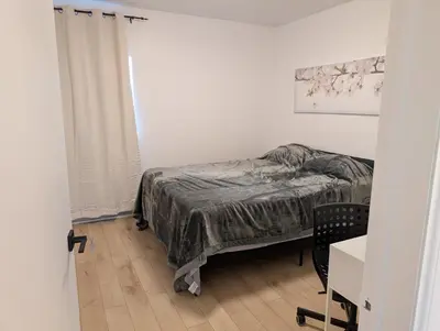 a bedroom with a bed and a table and a chair at Stay close to Montreal in Longueuil
