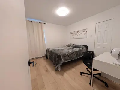a bedroom with a bed and a desk and a chair at Stay close to Montreal in Longueuil