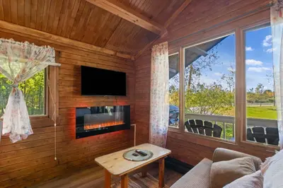 a living room with a fireplace and a tv at Chalet 1 cuisine - Domaine de l'Archipel in Sorel