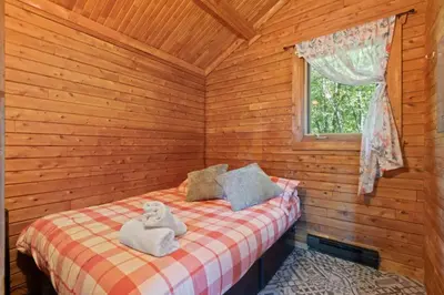 a bedroom with a bed in a wooden cabin at Chalet 1 cuisine - Domaine de l'Archipel in Sorel