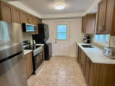 a kitchen with wooden cabinets and a stainless steel refrigerator at Chic 3BR 5 Beds 5min walk to Metro Free Parking in Laval