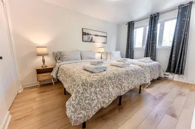 two beds in a bedroom with two lamps and two beds sidx sidx sidx at Chic 3BR 5 Beds 5min walk to Metro Free Parking in Laval
