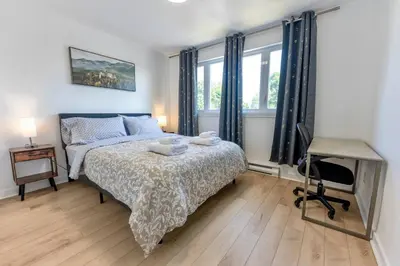 a bedroom with a bed and a desk and windows at Chic 3BR 5 Beds 5min walk to Metro Free Parking in Laval
