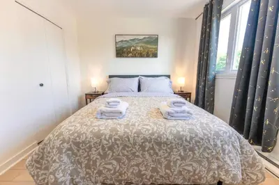 a bedroom with a bed with two towels on it at Chic 3BR 5 Beds 5min walk to Metro Free Parking in Laval