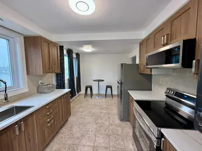 a kitchen with wooden cabinets and a stainless steel refrigerator at Chic 3BR 5 Beds 5min walk to Metro Free Parking in Laval