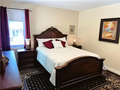 a bedroom with a large bed and a window at Cozy Stay with Balcony, BBQ & Trails, Near Lake Lyster in Coaticook