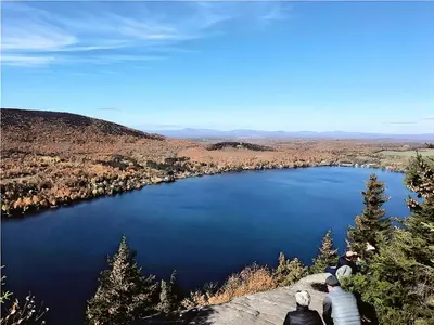a group of people sitting on a rock overlooking a lake at Cozy Stay with Balcony, BBQ & Trails, Near Lake Lyster in Coaticook