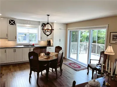 a kitchen and dining room with a table and chairs at Cozy Stay with Balcony, BBQ & Trails, Near Lake Lyster in Coaticook