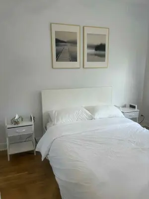 a bedroom with a white bed with two pictures on the wall at Cozy 1BDR in Prime location - Walk to Everything in Montréal