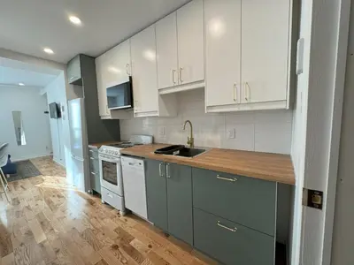 a kitchen with white cabinets and a wooden floor at Appartement simple ou double 2313#1M in Montréal
