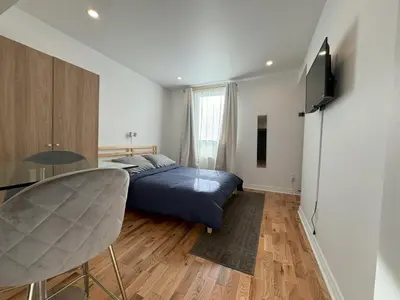 a bedroom with a bed and a table and a television at Appartement simple ou double 2313#1M in Montréal