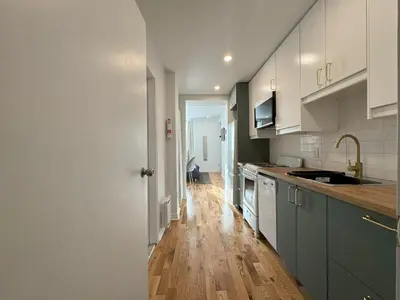 a kitchen with white cabinets and a wooden floor at Appartement simple ou double 2313#1M in Montréal