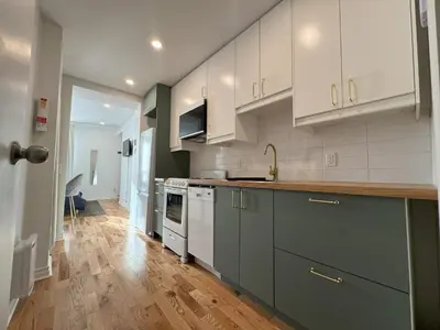 a kitchen with white cabinets and a wooden floor at Appartement simple ou double 2313#1M in Montréal