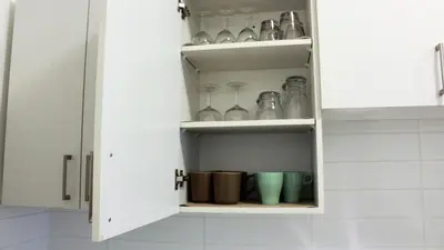 a white kitchen cabinet with glass items in it at Appartement simple ou double 2313#1M in Montréal
