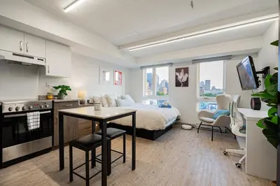 a bedroom with a bed and a kitchen with a table at Top Location - Cozy & Bright MTL studio near metro in Montréal