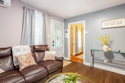 a living room with a leather couch and a table at Appartement moderne 3 chambres avec spa, jardin privé & parking gratuit - accès autonome in Saint-Jean-sur-Richelieu